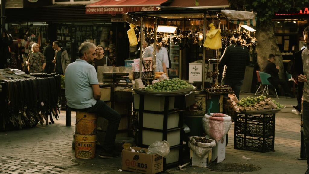 An urban vendor stall in a busy market with diverse shoppers and fresh produce.