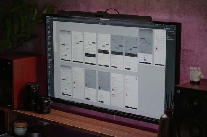 Stylish home office desk with a large monitor displaying UI designs.