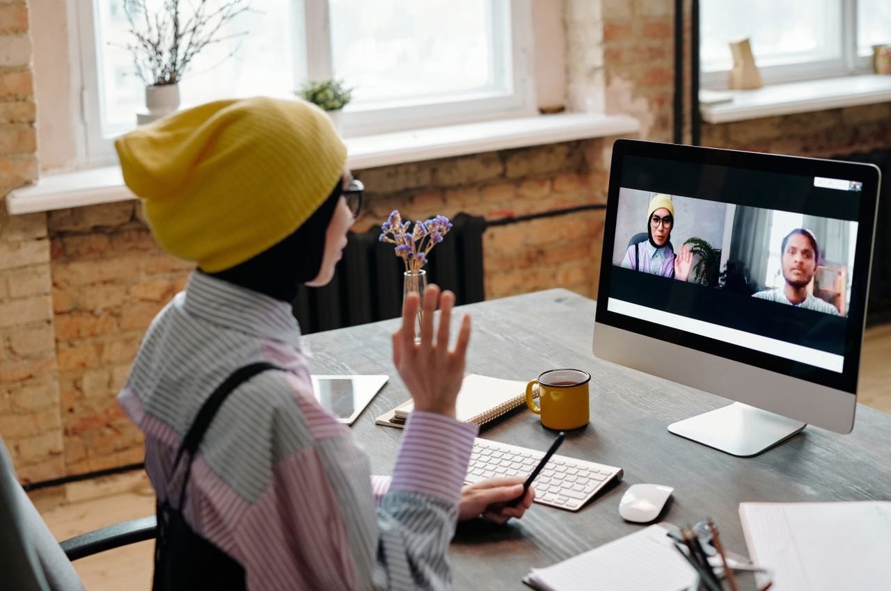 Adult woman engaged in a video call meeting from a cozy office environment, showcasing remote work dynamics.