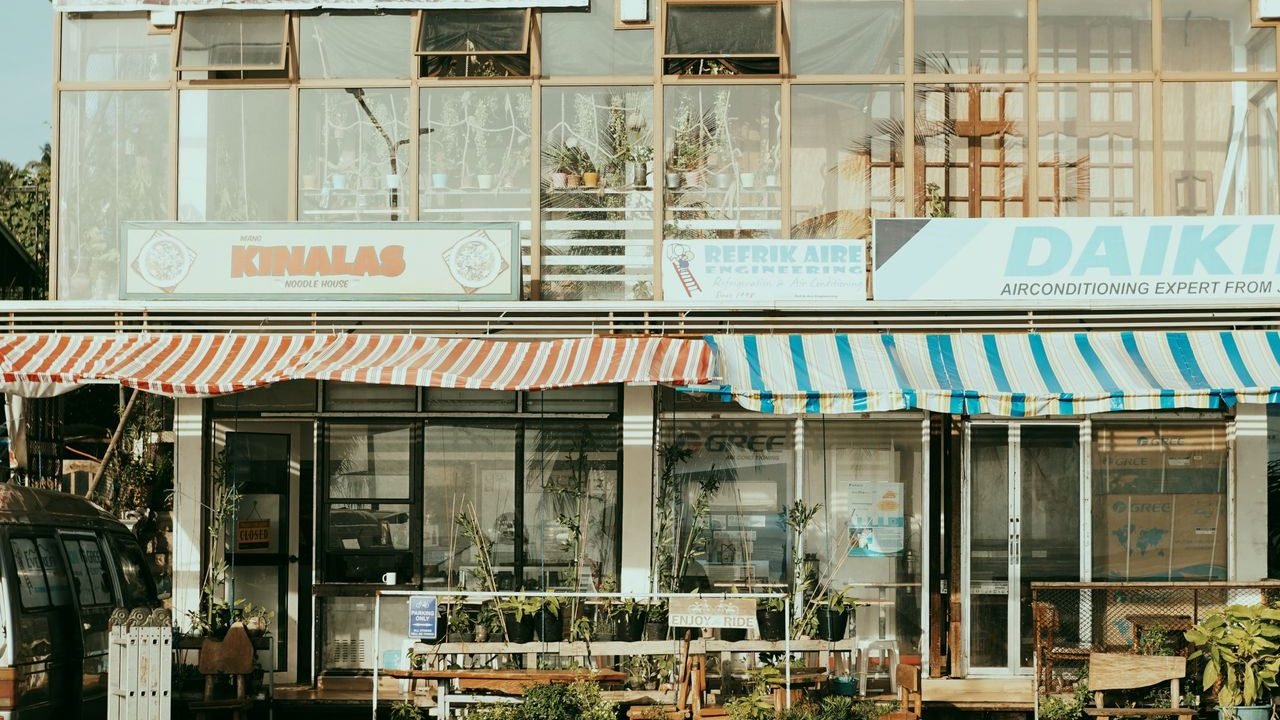 Charming street scene featuring local shops with colorful striped awnings and outdoor plants.